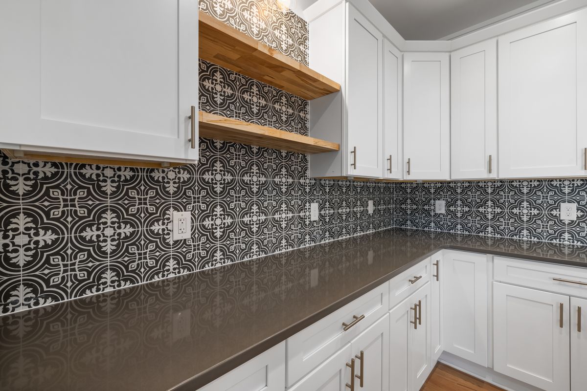 White shaker kitchen cabinets with brass pulls and open wood shelves