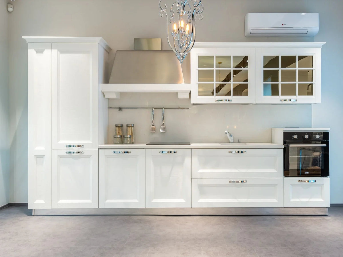 Modern white kitchen cabinets with glass-front uppers and sleek hardware in a bright renovated kitchen