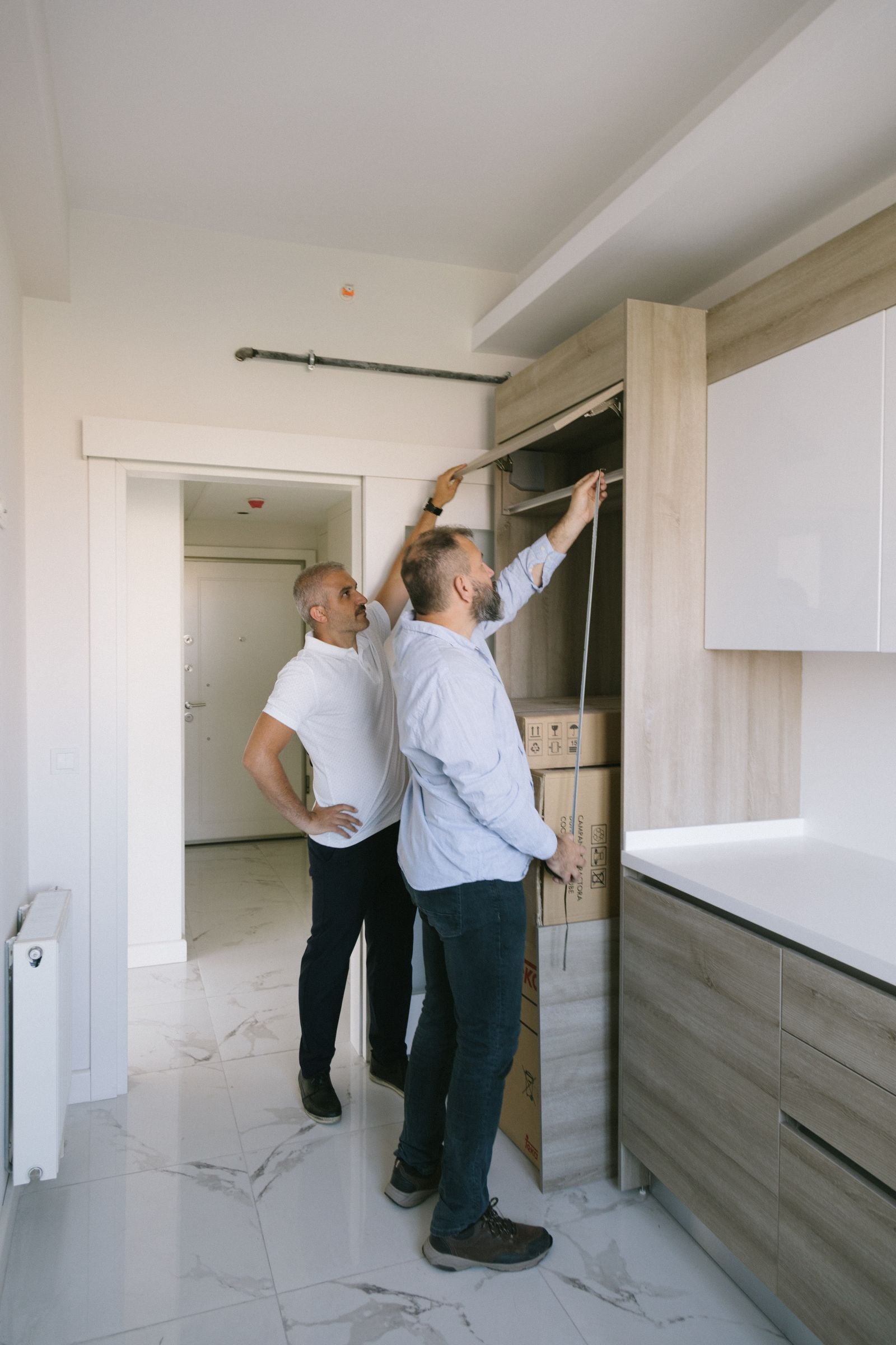 Two people measuring a cabinet opening for a custom cabinet quote