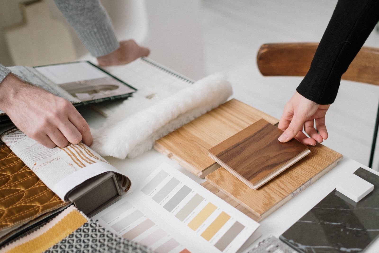 Hands comparing wood, stone, fabric, and finish samples